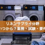 業務用洗濯機の前に置かれた白いシーツのカート